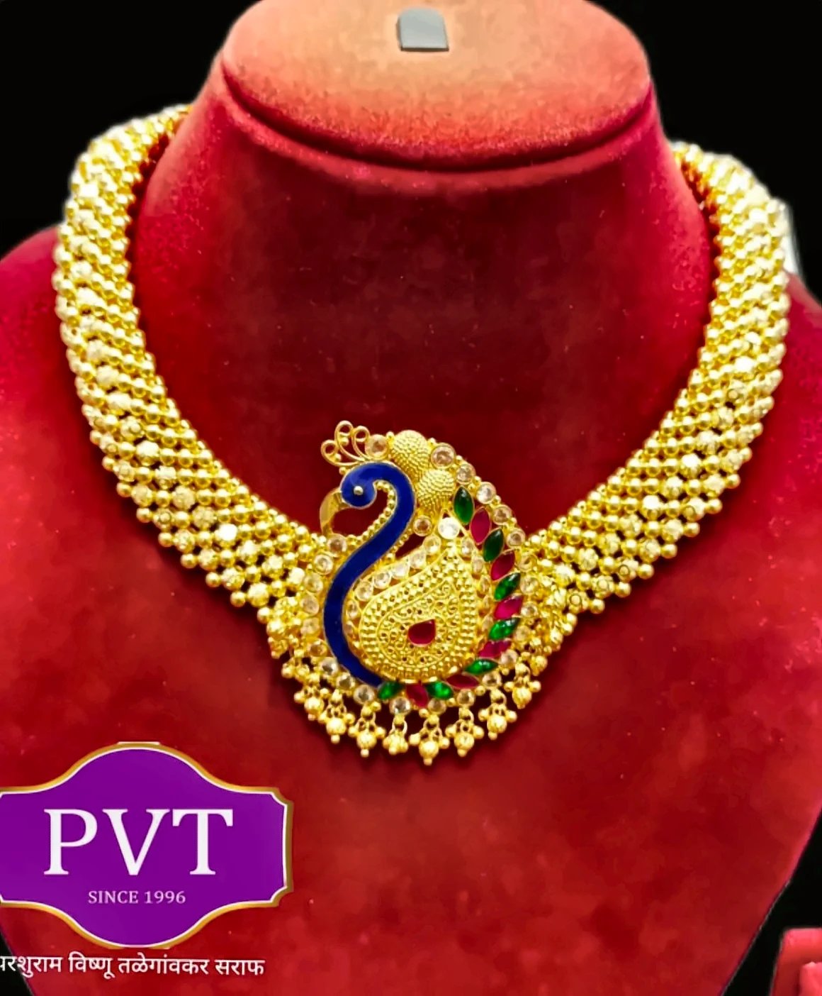 Gold choker necklace with a peacock pendant in blue, green and pink stones
